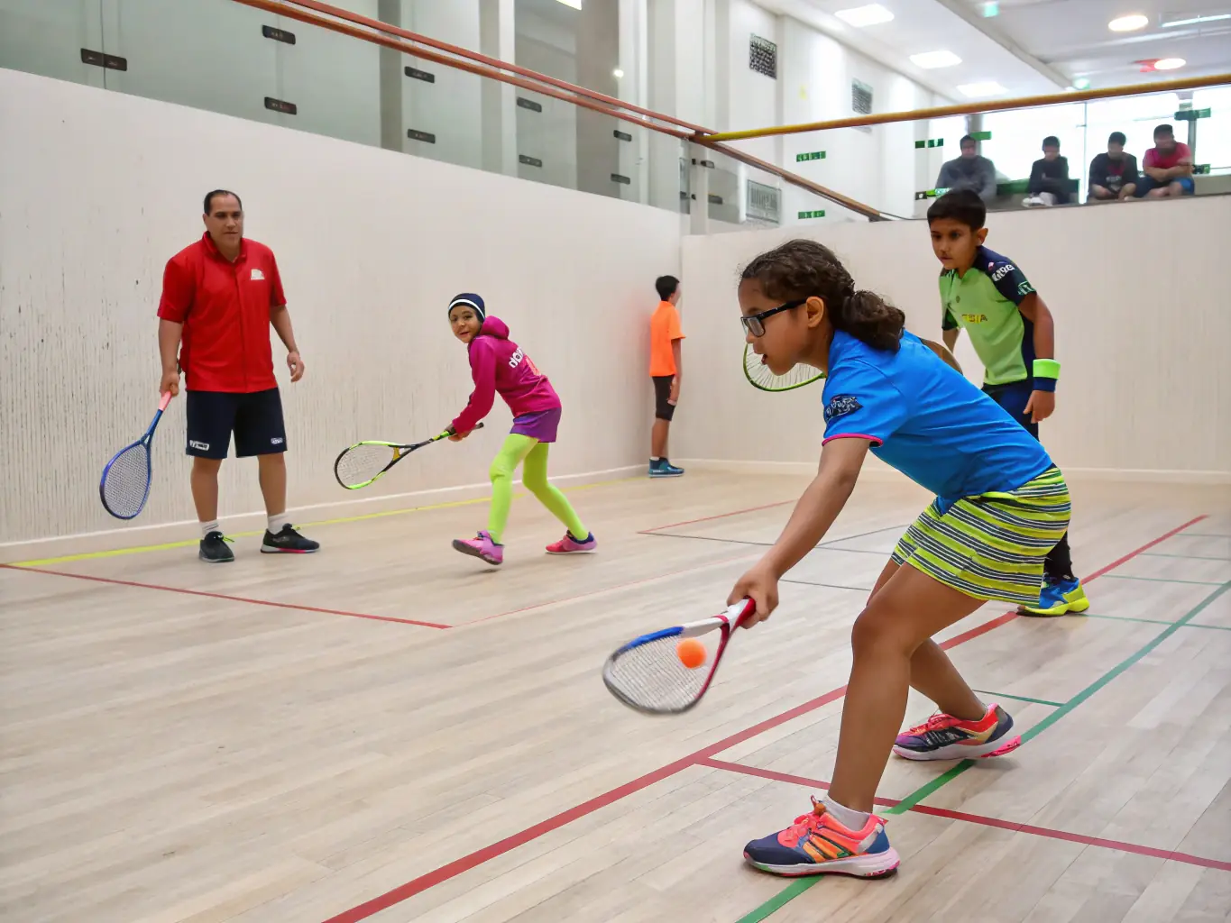 An action shot of young badminton players participating in a training session at the Andrézieux-Bouthéon Badminton Club's junior program, emphasizing skill development and teamwork.